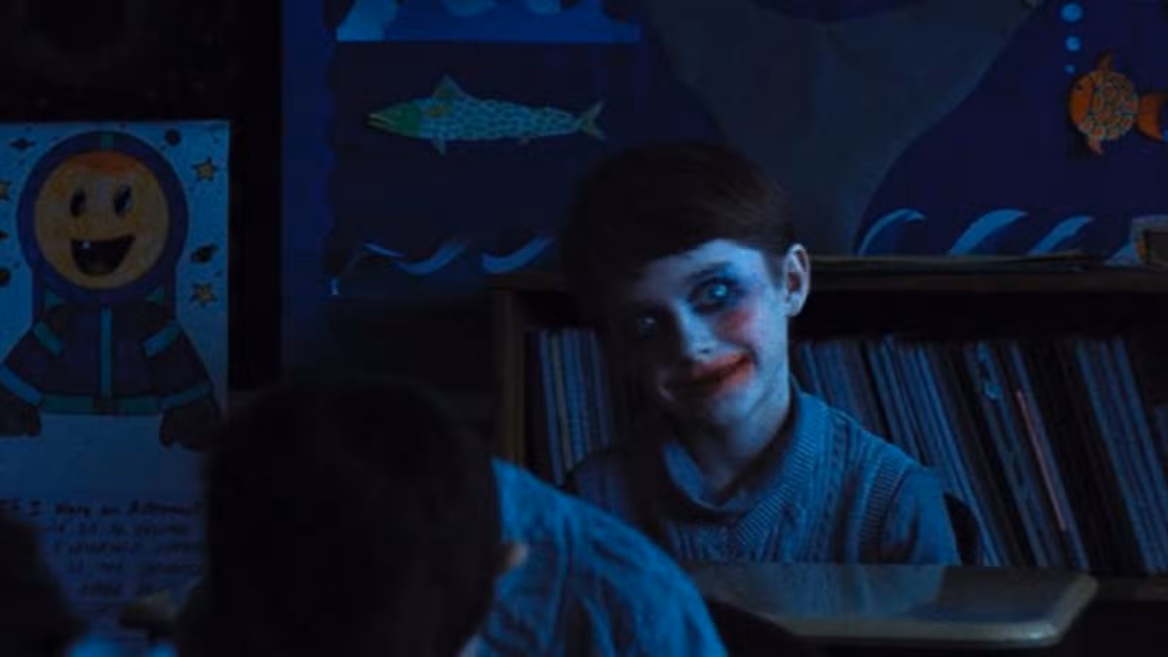 یک پسر بچه با لبخندی ترسناک و گریمی شبیه به دلقک در صحنهای تاریک از فیلم Weapons.