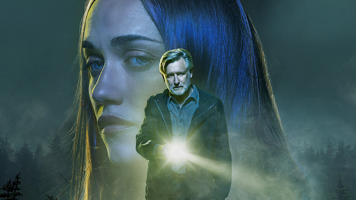 بیل پولمن در نقش کارآگاه هری امبروز در سریال گناهکار، با چراغ قوه در حال تحقیق در یک صحنه تاریک است.