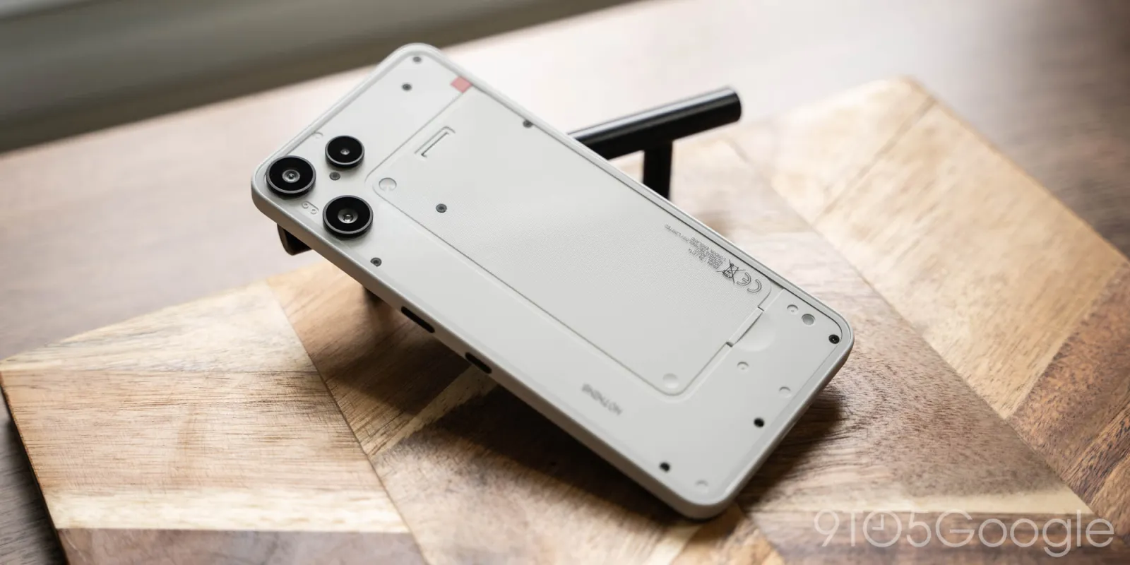 نمای کامل پنل پشتی شفاف گوشی ناتینگ فون 3a لایت سفید روی یک سطح سنگی.